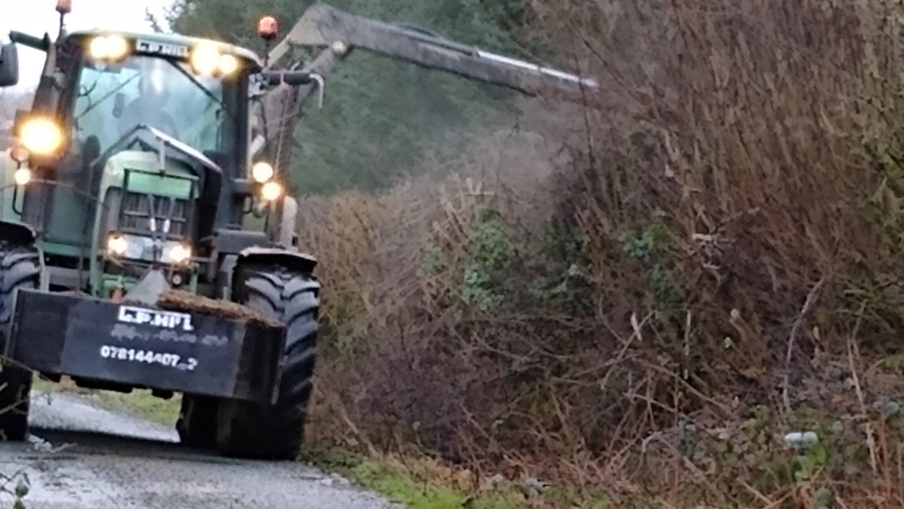 tractor cutting a hedge from the road